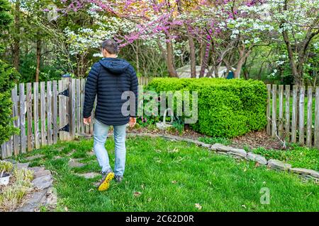 Giardino in Virginia con recinzione di legno e uomo a piedi da cespugli e dogwood bianco e fiori di primavera rosa rosso redbud su alberi Foto Stock