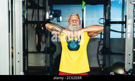 Hipster senior man training Inside gym - persona tatuata matura divertirsi facendo esercizi di allenamento in sport fitness club - vita attiva gioiosa anziani Foto Stock