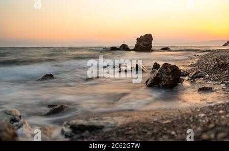 Fotografare le onde che colpiscono le rocce in un tempo tempestoso con una lunga esposizione Foto Stock