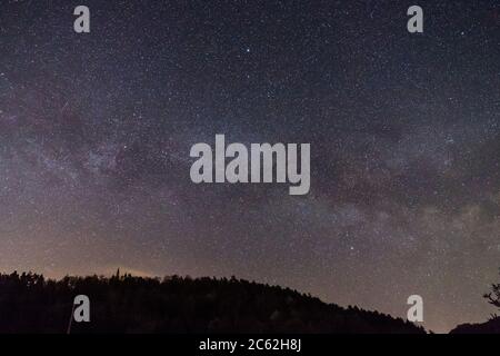 Germania, campo di stelle in movimento di via lattea nucleo galassia su alb sveva silhouette di alberi foresta e famoso antico castello teck sulla cima di una collina di notte Foto Stock