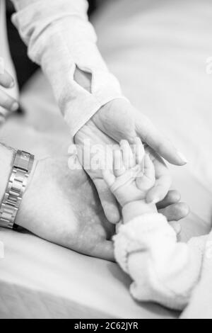 Mani di mamma e papà che tengono la mano del bambino. La mano di madre e padre che tiene la mano minuscola del bambino Foto Stock