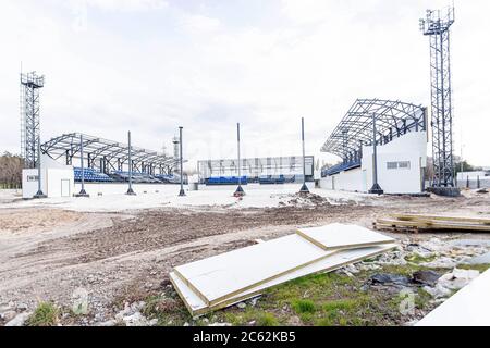 Nuovo e piccolo stadio per giochi estivi in costruzione circondato da recinzione in una giornata nuvolosa di primavera. Concetto di idea di progettazione, sfondo Foto Stock