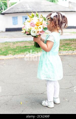 Bambina in bel vestito che tiene il colorato bouquet di fiori di nozze in mani. Concetto di idea di matrimonio, primo piano Foto Stock