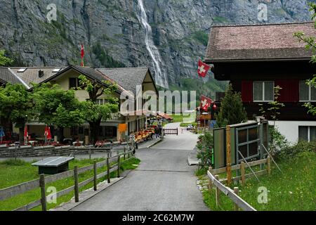 Vista di un bar e ristorante a Stechelberg un piccolo insediamento alla testa della valle di Lauterbrunnen in Svizzera, con una cascata nel backgro Foto Stock