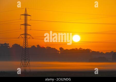 Torre di trasmissione che emerge dalla nebbia all'alba Foto Stock