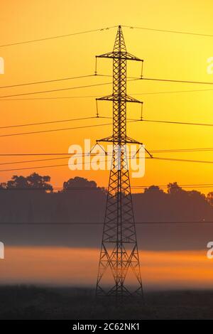 Torre di trasmissione che emerge dalla nebbia all'alba Foto Stock