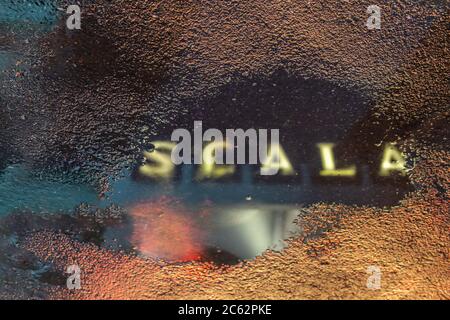 Il riflesso del logo del cinema Scala in un pozze d'acqua dopo la pioggia. Foto Stock