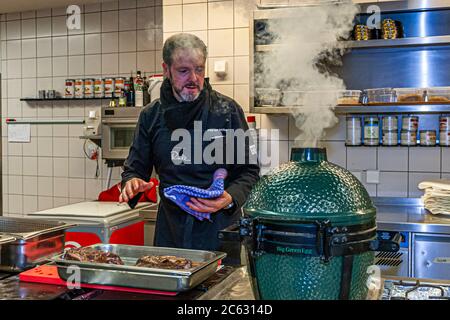 Tedesco 3 stelle Michelin chef Marco Müller con Big Green Egg. Uno dei segreti del brisket tenero di manzo è l'ordine 'verso': Prima scaldare nel forno a fuoco basso e poi grigliarlo caldo nel suo proprio fumo appena prima di tagliarlo Foto Stock