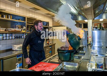 Tedesco 3 stelle Michelin chef Marco Müller con Big Green Egg. Uno dei segreti del brisket tenero di manzo è l'ordine 'verso': Prima scaldare nel forno a fuoco basso e poi grigliarlo caldo nel suo proprio fumo appena prima di tagliarlo Foto Stock