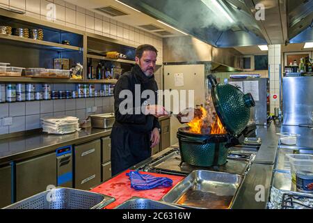 Tedesco 3 stelle Michelin chef Marco Müller con Big Green Egg. Uno dei segreti del brisket tenero di manzo è l'ordine 'verso': Prima scaldare nel forno a fuoco basso e poi grigliarlo caldo nel suo proprio fumo appena prima di tagliarlo Foto Stock