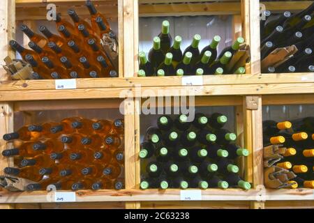 Varietà di bottiglie di vino conservate su un rack di legno in una cantina Foto Stock