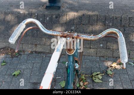 una vista ravvicinata di una vecchia bicicletta arrugginita che è stata abbandonata e bloccata a un rastrello in città Foto Stock