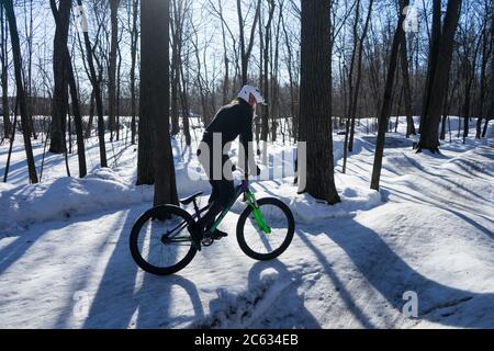 Un uomo in inverno fa una bicicletta su una pista a pompa in un casco. Foto Stock