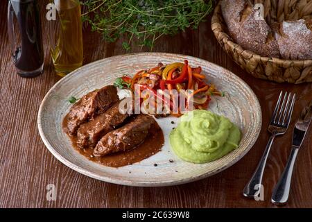 Guance di manzo brasate tradizionali tedesche in salsa marrone con funghi e purè di patate come closeup su una piastra dal design moderno Foto Stock