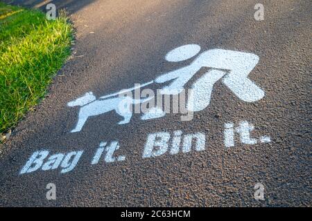 BAG IT Bin ha dipinto il segno sul sentiero, incoraggiando i proprietari di cani a pulire dopo il loro animale domestico Foto Stock