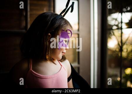 Ragazza giovane in abito su guardando fuori porta anteriore Foto Stock