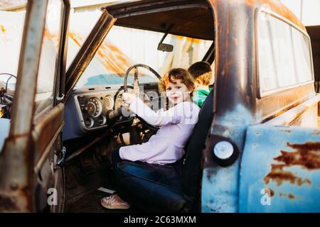 Fratello e sorella giovani seduti in camion d'epoca al tramonto Foto Stock