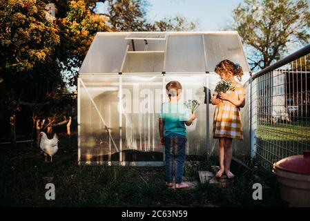 Bambini giovani in piedi fuori cortile verde casa con fiori Foto Stock