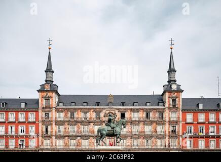 Dal basso del famoso edificio Casa de la Panaderia e la statua di bronzo di Re Filippo III contro il cielo nuvoloso a Madrid Foto Stock