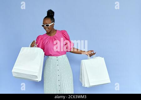 Donna africana entusiasta che guarda all'interno borse per la spesa isolato su viola. Foto Stock