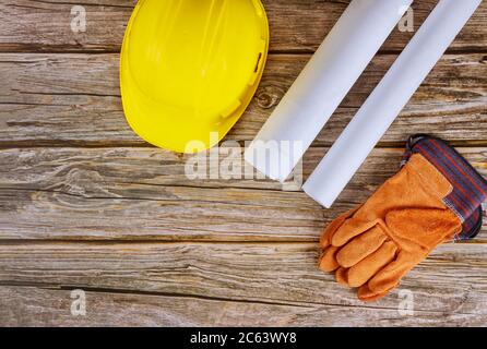 Costruttore di architetti progetta lavorando su progetti di costruzione di uffici di ingegneria piani di sicurezza guanti su elmetto di sicurezza giallo Foto Stock