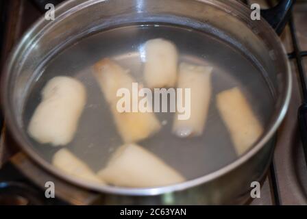 Cottura manioca in una pentola con acqua bollente, esculenta Manihot. Manioca, chiamata anche mandioca, yuca, balinghoy, mogo, mandioca, kamoteng kahoy, tapioc Foto Stock