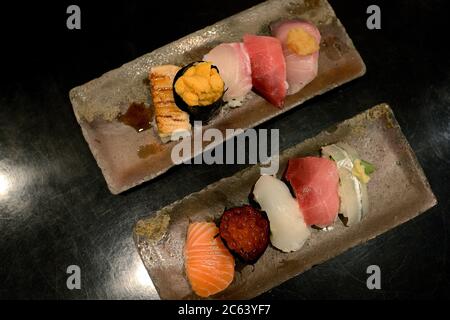 Il set di sushi premium è collocato su una piastra di pietra nera. Vista dall'alto, immagine a toni scuri. Foto Stock