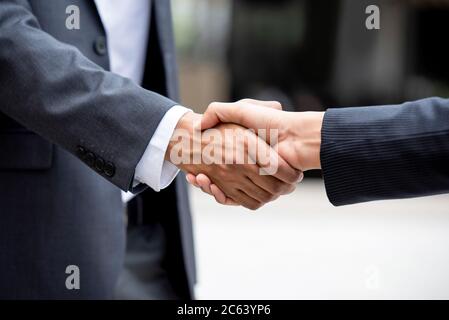 Uomo d'affari in abito formale facendo stretta di mano con partner all'aperto Foto Stock