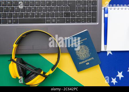 Vista dall'alto degli oggetti da viaggio: Passaporto brasiliano, notebook, occhiali da sole, chiavi, carta di credito, blocco note, penna, denaro e bandiera brasiliana sullo sfondo. Tra Foto Stock