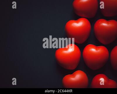 Cuori rossi su sfondo nero con spazio per la copia. Molte sfere rosse in schiuma con forma a cuore. Amore, cura e concetto di San Valentino. Foto Stock