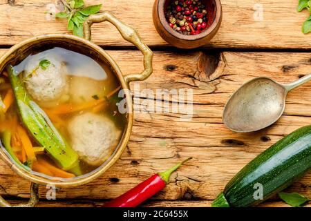 Ciotola di zuppa con polpette e verdure su tavola di legno retrò. Zuppa con zucchine e polpette Foto Stock