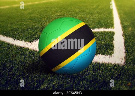 Tanzania bandiera sulla palla in posizione di calcio d'angolo, campo di calcio sfondo. Tema nazionale del calcio sull'erba verde. Foto Stock