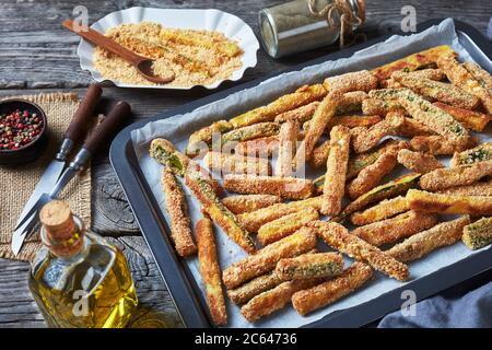 Grissini croccanti di zucchine impanati con panko, parmigiano, spezie su una griglia da forno, sano spuntino estivo, primo piano. Vista panoramica Foto Stock