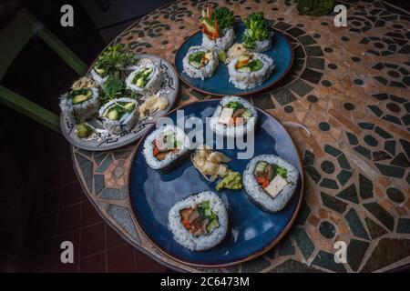 Panini di sushi vegano fatti in casa con riso, alghe, tofu, avocado e altri sapori. Foto Stock