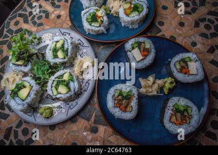 Panini di sushi vegano fatti in casa con riso, alghe, tofu, avocado e altri sapori. Foto Stock