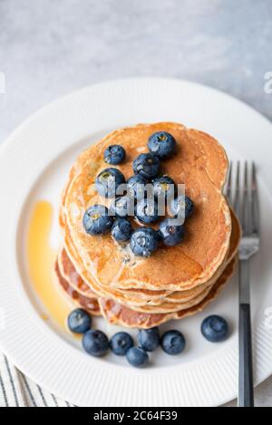 Gustosi pancake di grano integrale con mirtilli e sciroppo d'acero su piatto bianco Foto Stock