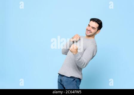 Felice uomo caucasico vincente facendo pugno pugno gesto isolato su sfondo azzurro chiaro Foto Stock