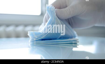 Il medico verifica un pacchetto di maschere chirurgiche controllandole una alla volta Foto Stock