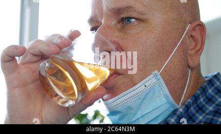 Ubriaco con maschera di protezione sul viso bere un bicchiere con alcol in un bar Foto Stock