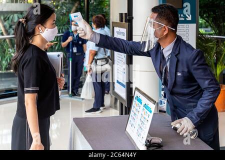 Guardia di sicurezza che controlla la temperatura del pubblico all'ingresso del centro commerciale durante la pandemia covid 19, Bangkok, Thailandia Foto Stock