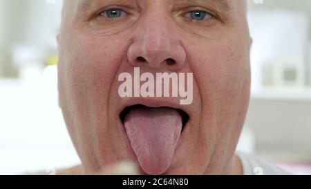 Primo piano immagine con un anziano uomo d'affari espressione viso preparazione a prendere una pillola. Foto Stock