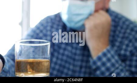 Ubriaco con maschera di protezione sul viso bere un bicchiere con alcol in un bar Foto Stock