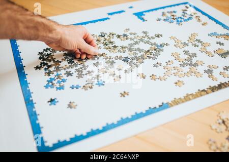 Un puzzle complesso su un tavolo bianco - molti pezzi solidi simili - un compito faticoso Foto Stock