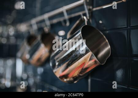 Caraffe da caffè in acciaio inox lucidato - utensili da barista sul posto di lavoro - macchine da caffè professionali e accessori Foto Stock