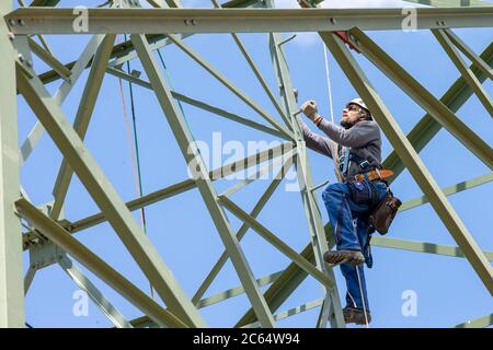 Heidenau, Germania. 06 luglio 2020. Un tecnico sale sul polo di potenza fino al suo posto di lavoro. A Heidenau, vicino a Dresda, in Sassonia, è in corso la costruzione di una nuova linea elettrica con tralicci elettrici più potenti per il trasporto di energia elettrica tra la Germania settentrionale e quella meridionale. Registrato in una riunione stampa con l'operatore di rete 50 Hertz. Credit: Daniel Schäfer/dpa-Zentralbild/ZB/dpa/Alamy Live News Foto Stock