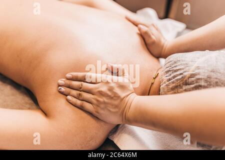 Mani di un massaggiatore professionista al lavoro - un effetto profondo e duro sui muscoli e sui tessuti di una persona Foto Stock
