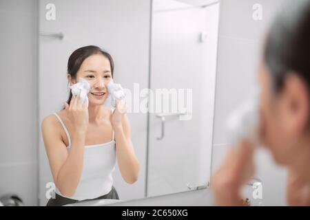 Donna skincare lavaggio viso in doccia schiuma viso lavaggio sapone strofinare sulla pelle. Godersi un po' di relax Foto Stock