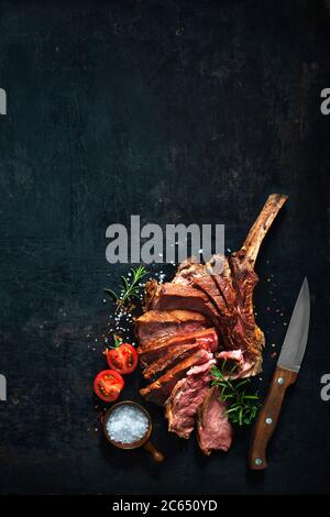 Bistecca di manzo di tomahawk stagionato alla griglia, tagliata a fette su sfondo scuro Foto Stock