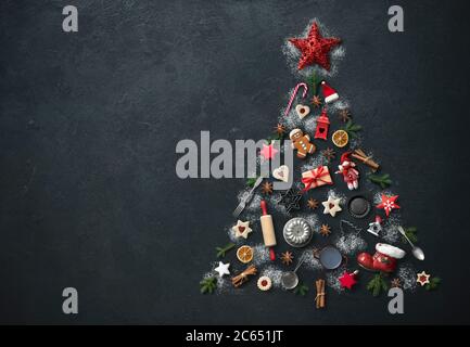 Sfondo di cottura natalizio con abete fatto da utensili da cucina, biscotti, spezie, bastoncini di cannella, stelle di anice, vista dall'alto Foto Stock