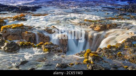 Onde oceaniche che riempia il pozzo di lava di Pele vicino a Wawaloli Beach Sulla Big Island delle Hawaii Foto Stock